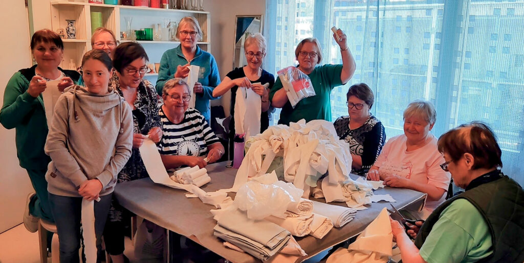 Ukrainalaisia ja vihtiläisiä kinnaslaisia ahkeroimassa vanhoista lakanoista siderullia sotilaille. Humanitaarinen toimintaryhmä Kinnas on jo kolmen vuoden ajan lähettänyt avustustavaraa Ukrainaan.